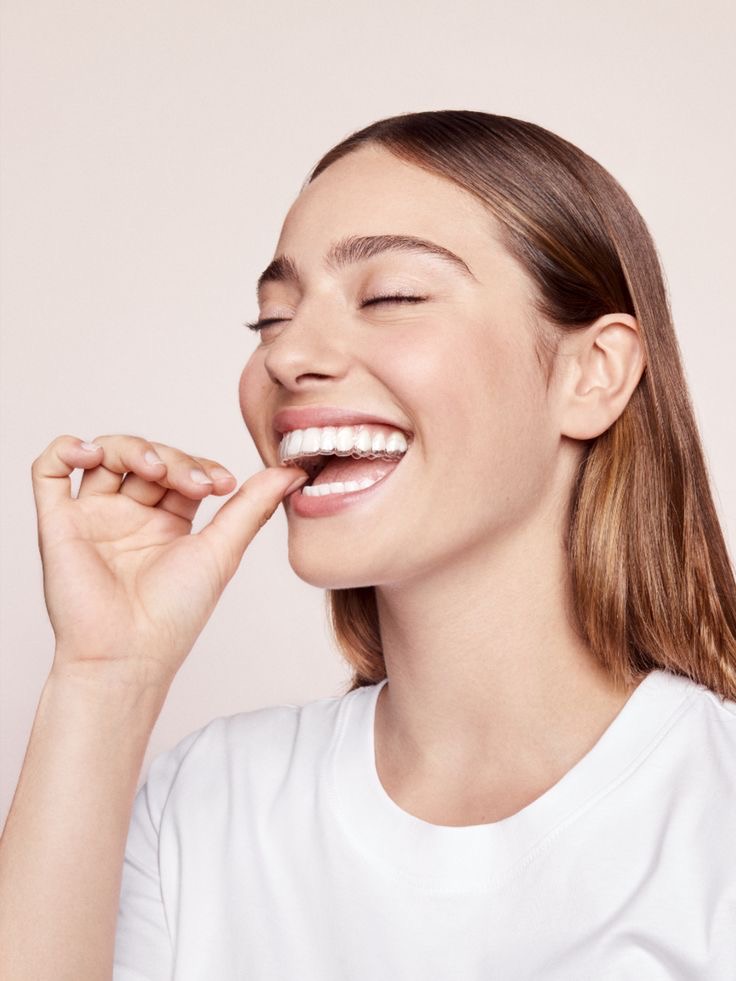 Smiling patient placing her Invisalign aligner